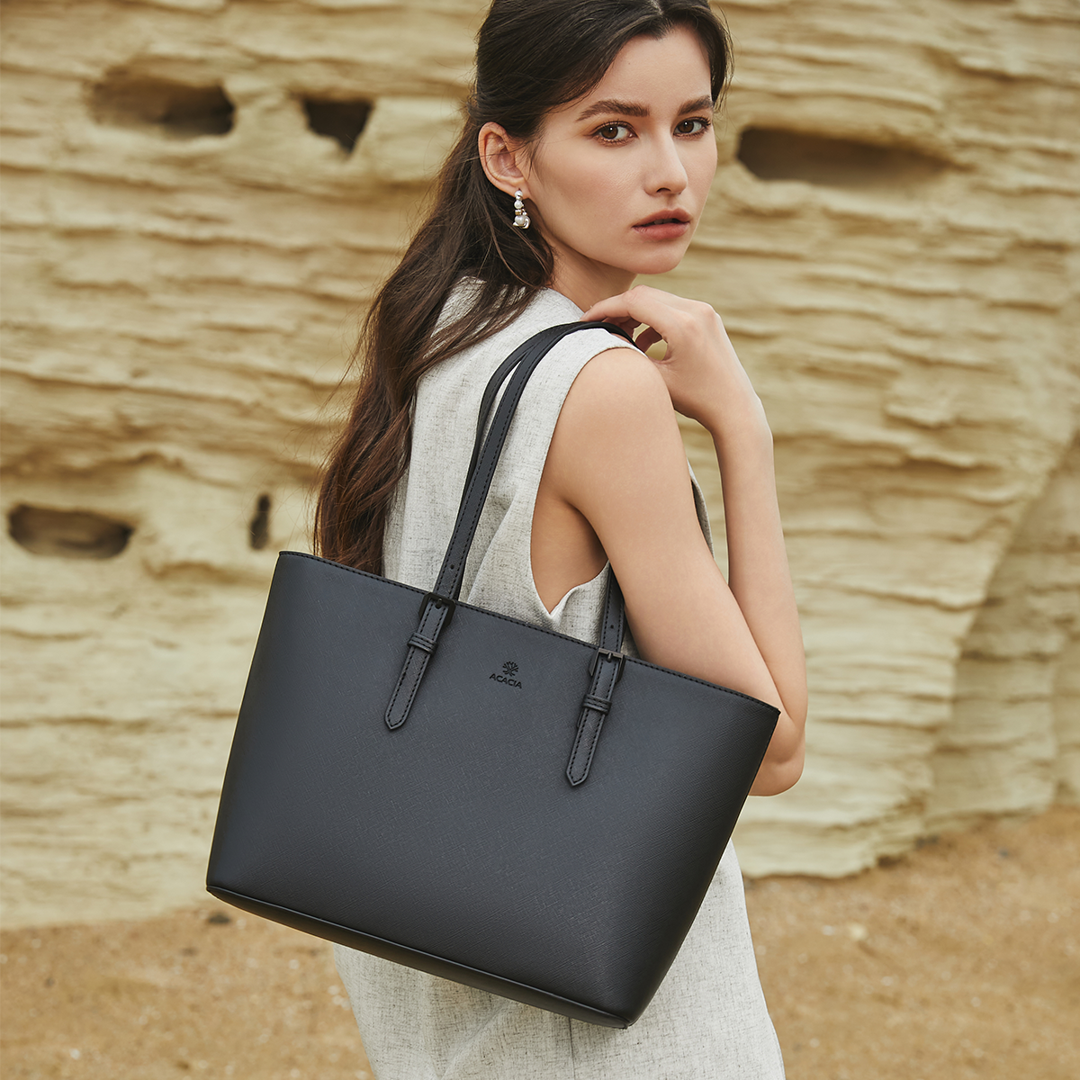 Handheld model photo of the Cedar tote bag showcasing its clean Japanese minimalist silhouette, rigid anti-scratch waterproof leather and professional look for working women.