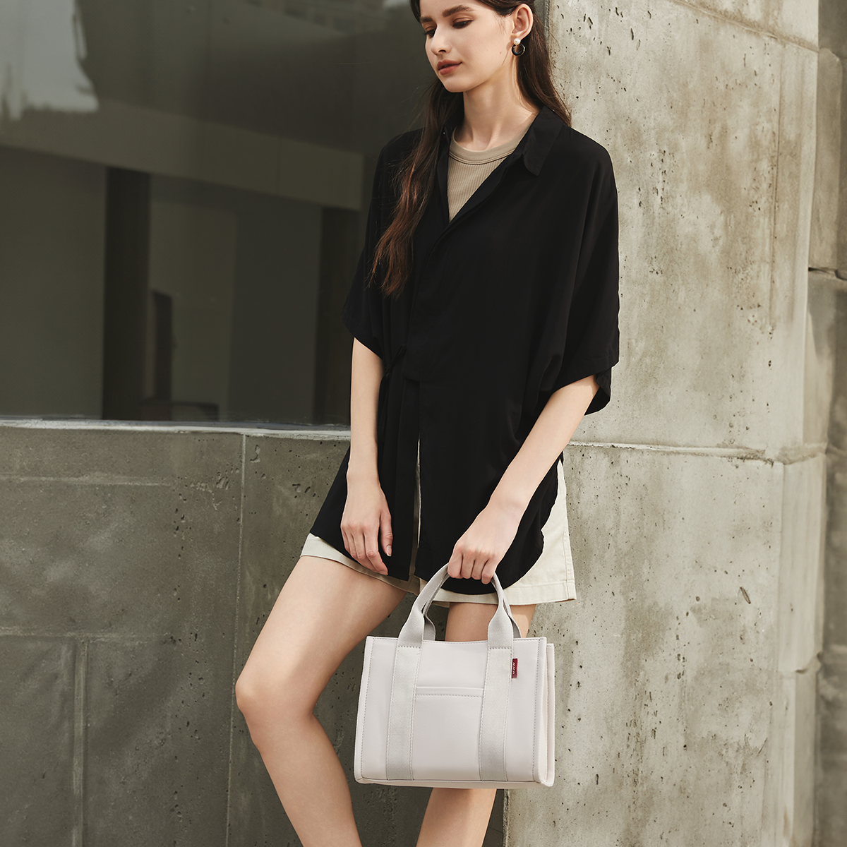 Handheld view of the ACACIA Fern Mini Tote. Premium PU leather feel, structured silhouette, and compact shape that accommodates an 11-inch notepad. Minimalist urban tote with crossbody option.