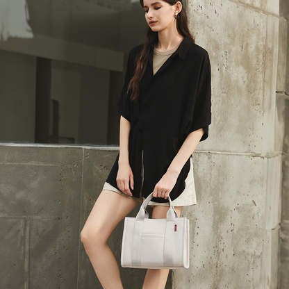 Handheld view of the ACACIA Fern Mini Tote. Premium PU leather feel, structured silhouette, and compact shape that accommodates an 11-inch notepad. Minimalist urban tote with crossbody option.