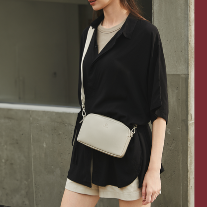 Light beige ACACIA Moss unisex crossbody bag in soft vegan leather. Features wide comfortable strap and double-zip compartments for daily essentials.