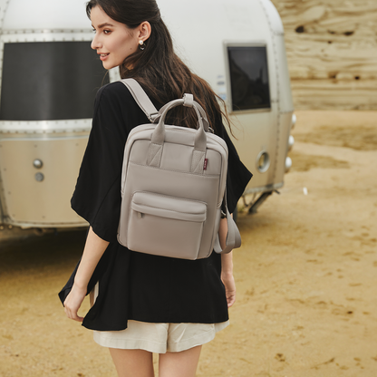 Model wearing the Reed Backpack in Moonstruck beige. A slim, structured unisex backpack offering a refined look with practical laptop storage. Ideal for students and daily commuters.