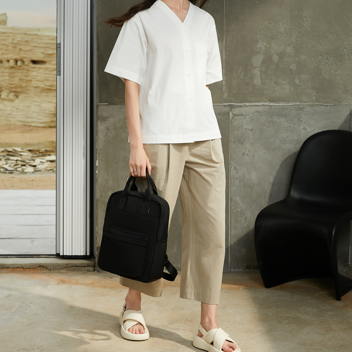Model using the Reed Backpack in black. A refined unisex backpack blending lightweight nylon and clean lines for an elevated everyday carry solution.